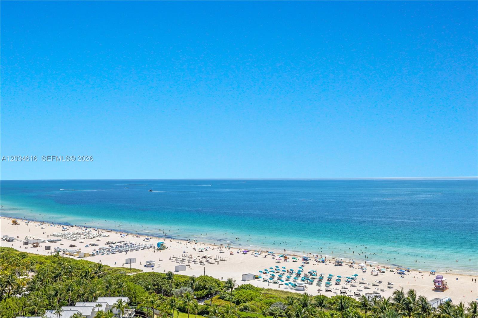 An elevated view of a sandy beach with umbrellas and the ocean under a clear sky — 100 S Pointe Dr # 1608, Miami Beach FL 33139, MIAMI BEACH, FL