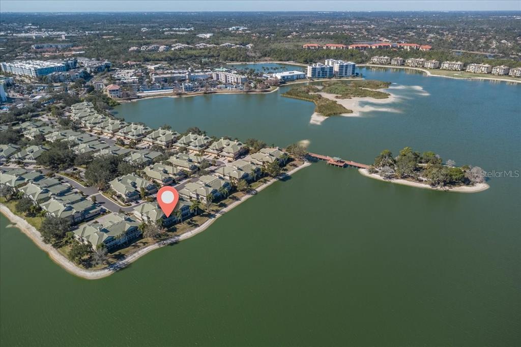 An aerial view shows a residential complex with townhomes situated along a large lake — 6515 MOORINGS POINT CIRCLE UNIT 102, LAKEWOOD RANCH, FL