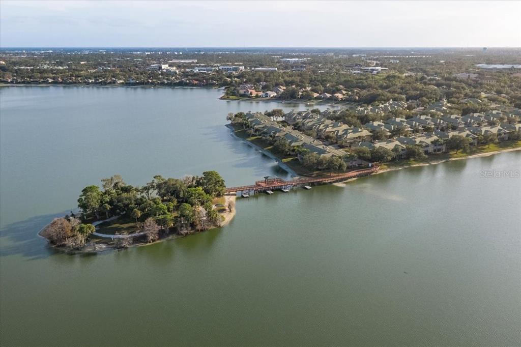 An aerial view shows a wooden footbridge connecting a residential complex to a small island — 6515 MOORINGS POINT CIRCLE UNIT 102, LAKEWOOD RANCH, FL