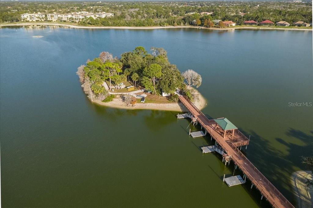 An aerial view shows a small, tree-covered island connected to the shore by a wooden pier — 6515 MOORINGS POINT CIRCLE UNIT 102, LAKEWOOD RANCH, FL
