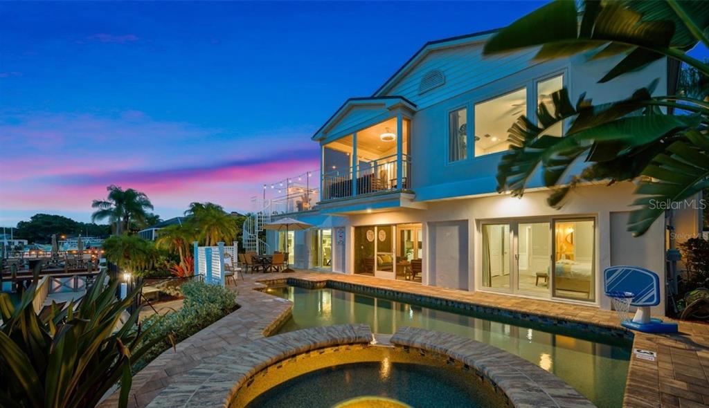 A two-story house exterior features a swimming pool, hot tub, and a screened-in balcony — 4545 HARBOR HILLS DRIVE, LARGO, FL