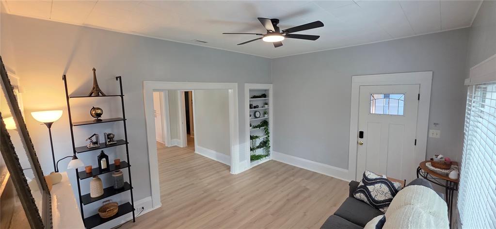 A living room features light-colored wood flooring, gray walls, a ceiling fan, and built-in shelving — 107 S 1ST STREET, HAINES CITY, FL