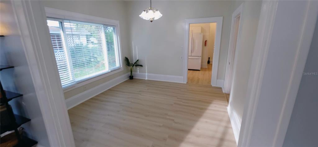 A dining room with light wood-look flooring, a large window with blinds, and a chandelier — 107 S 1ST STREET, HAINES CITY, FL