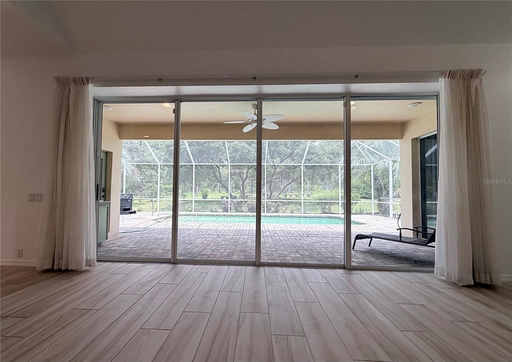 A room with light wood-look tile flooring features large sliding glass doors overlooking a pool — 4690 W TOMAHAWK DRIVE, BEVERLY HILLS, FL