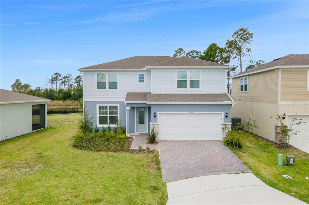A two-story house with blue and white siding, a two-car garage, and a paved driveway — 17315 MILLION LAKES COURT, CLERMONT, FL