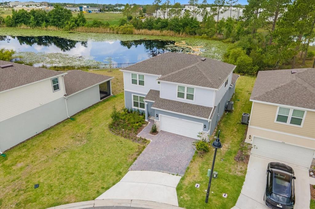 An aerial view shows a two-story house with a paved driveway next to a pond — 17315 MILLION LAKES COURT, CLERMONT, FL