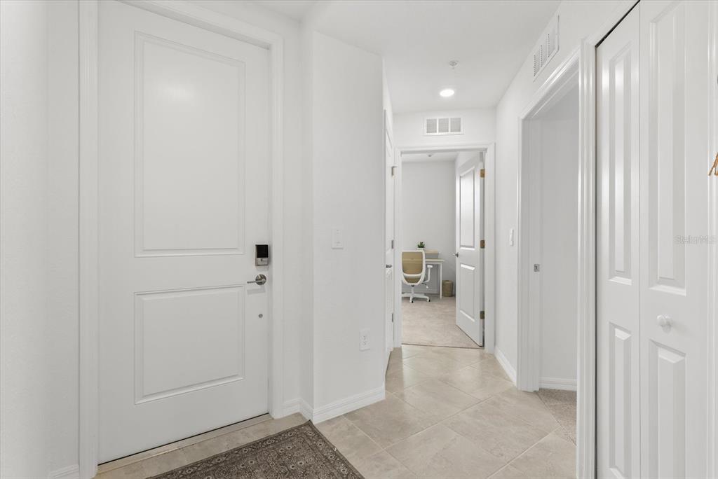 A white front door opens into a tiled entryway leading to a carpeted home office — 17570 OPAL SAND DRIVE UNIT 201, VENICE, FL