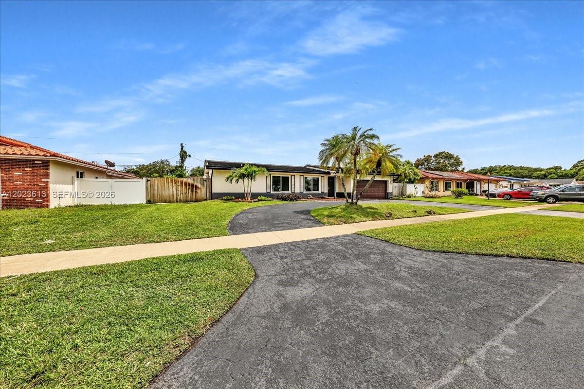 A single-story house with a circular driveway, palm trees, and a lawn under a blue sky — 5260 SW 10th Ct, Plantation FL 33317, PLANTATION, FL
