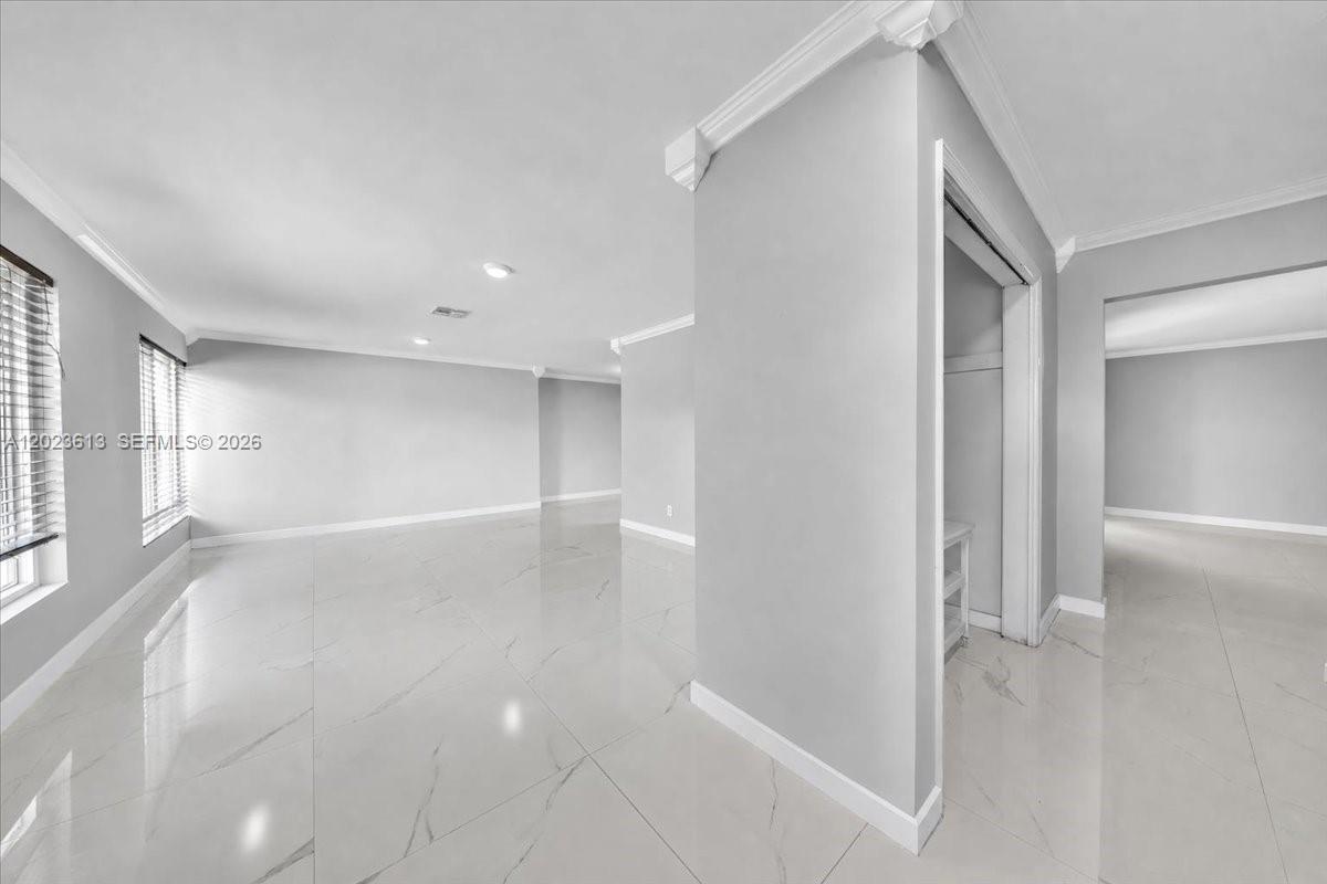 An empty room features light gray walls, white crown molding, and polished marble-look tile flooring — 5260 SW 10th Ct, Plantation FL 33317, PLANTATION, FL