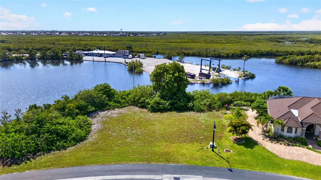 An aerial view shows a vacant residential lot next to a house and a marina — 5408 SEA EDGE DRIVE, PUNTA GORDA, FL