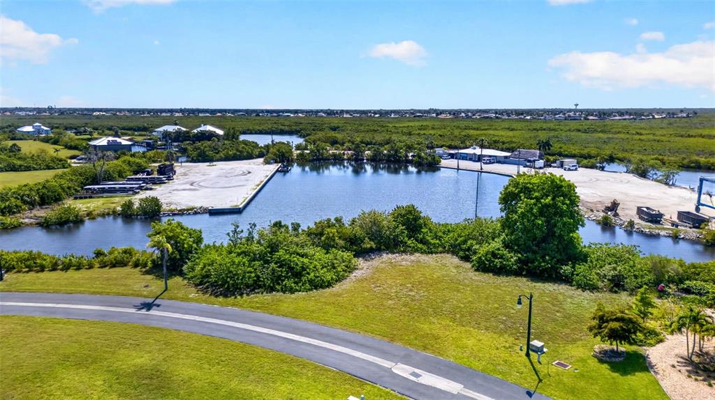 An aerial view shows a small marina basin surrounded by mangroves, paved lots, and greenery — 5408 SEA EDGE DRIVE, PUNTA GORDA, FL