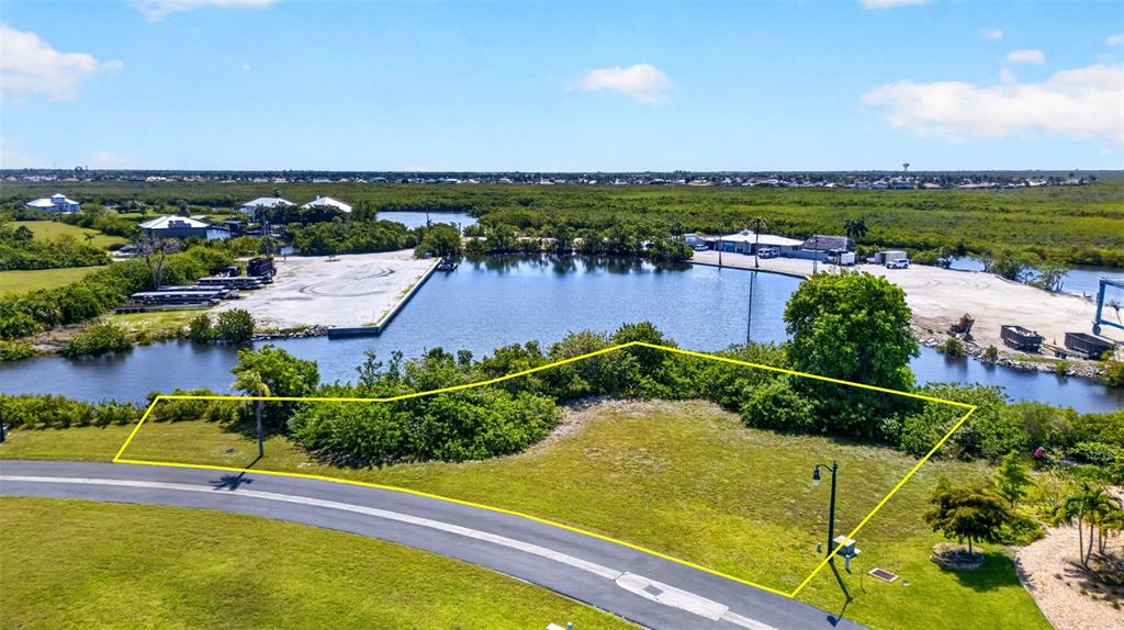 An aerial view shows a vacant, grassy lot outlined in yellow near a waterfront area — 5408 SEA EDGE DRIVE, PUNTA GORDA, FL