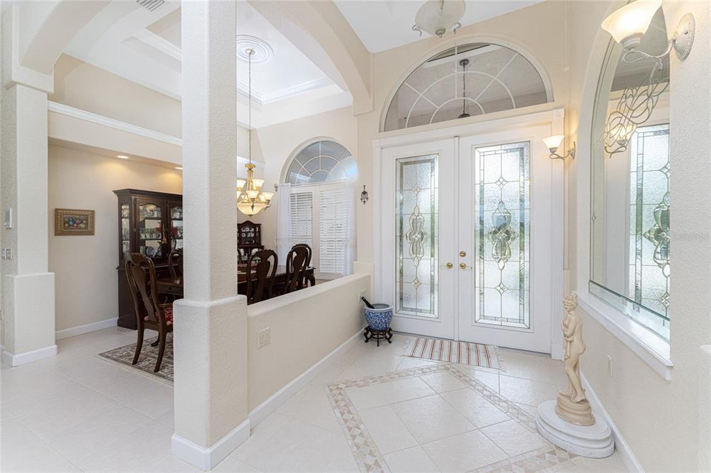 A tiled entryway features a double glass-paneled front door, a dining room, and a statue — 12109 SW KINGSWAY CIRCLE, LAKE SUZY, FL