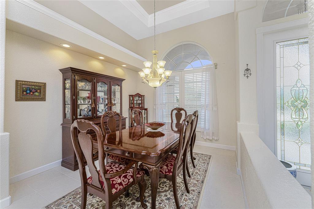 A formal dining room features a wooden table set, a hutch, and a chandelier — 12109 SW KINGSWAY CIRCLE, LAKE SUZY, FL