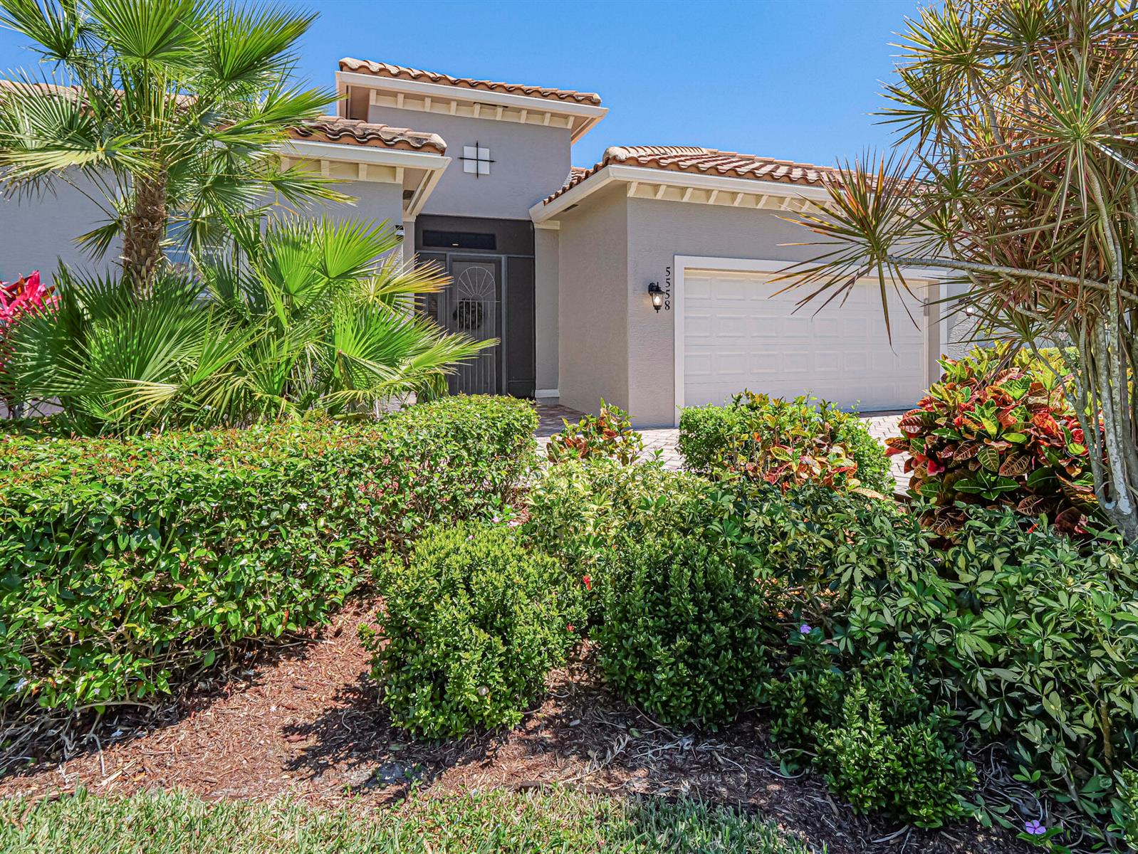 A single-story house with a beige stucco exterior, a tiled roof, and a front-facing garage — 5558 55th Avenue, Vero Beach FL 32967, VERO BEACH, FL