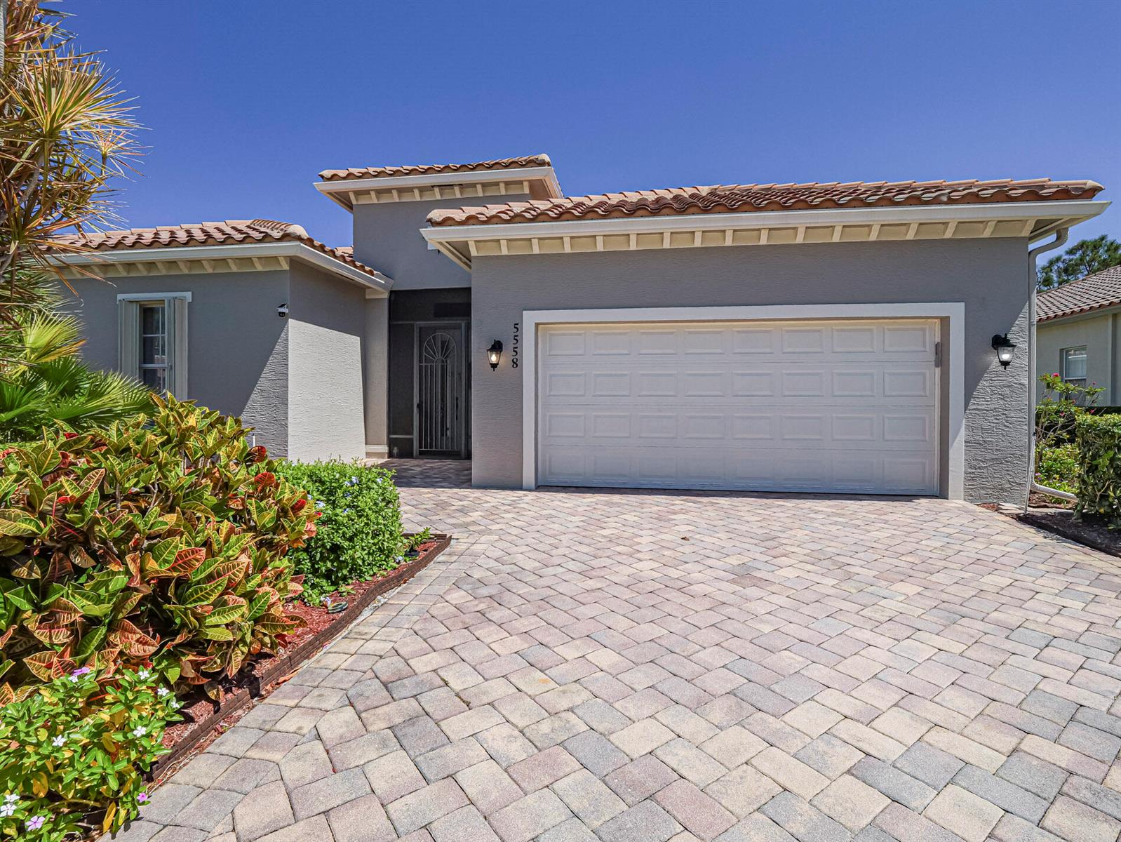 A single-story house with a gray stucco exterior, tile roof, and a paved driveway — 5558 55th Avenue, Vero Beach FL 32967, VERO BEACH, FL
