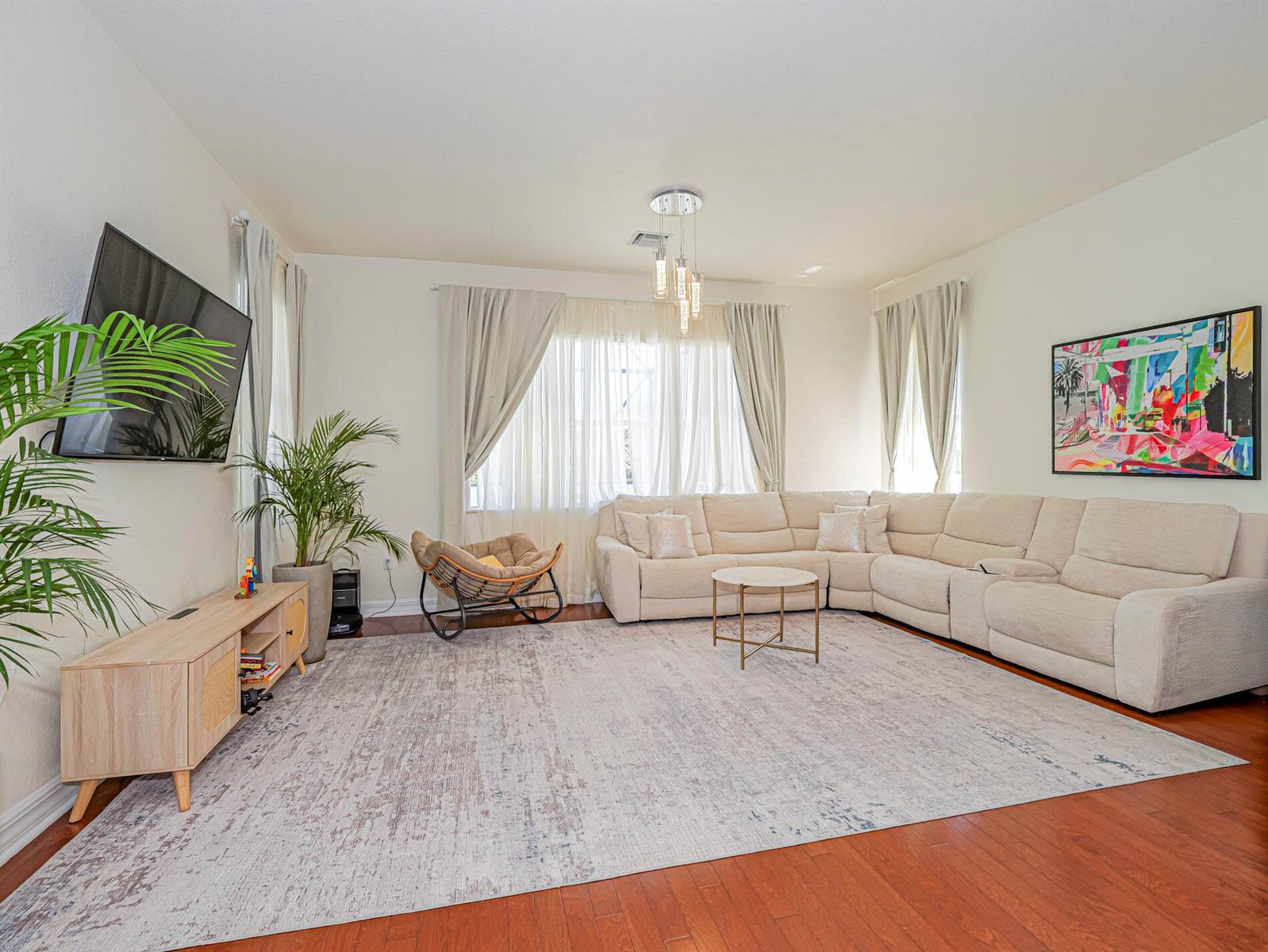A living room features a large beige sectional sofa, a patterned rug, and hardwood floors — 5558 55th Avenue, Vero Beach FL 32967, VERO BEACH, FL