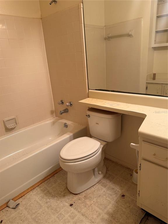A bathroom features a white bathtub, a toilet, and a vanity with a large mirror — 1401 S PALMETTO AVENUE UNIT 201, DAYTONA BEACH, FL