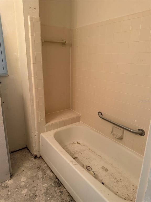 A beige tiled bathtub surround features a built-in shelf and a metal grab bar — 1401 S PALMETTO AVENUE UNIT 201, DAYTONA BEACH, FL