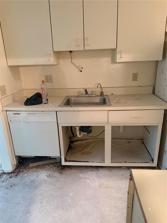 A kitchen features white cabinets, a sink, a dishwasher, and exposed plumbing under the counter — 1401 S PALMETTO AVENUE UNIT 201, DAYTONA BEACH, FL