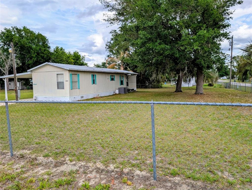 A yellow mobile home with a covered porch sits on a large, grassy lot — 14181 SE 90TH TERRACE, SUMMERFIELD, FL
