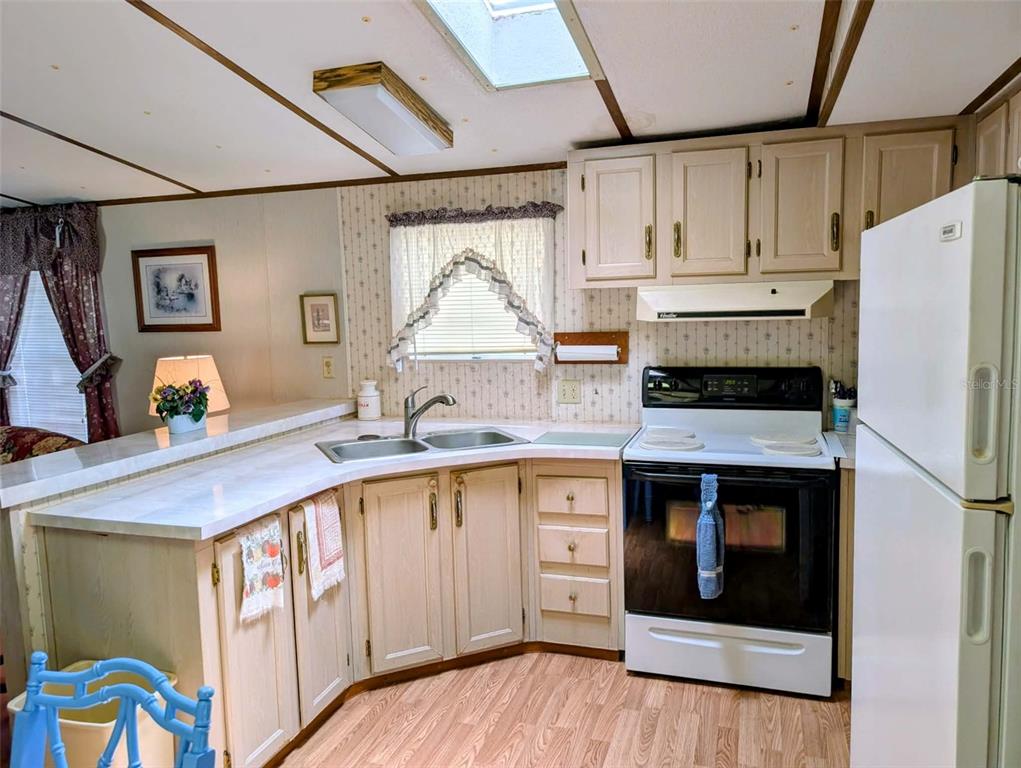 A kitchen features light wood cabinets, white countertops, a corner sink, and a white stove — 14181 SE 90TH TERRACE, SUMMERFIELD, FL