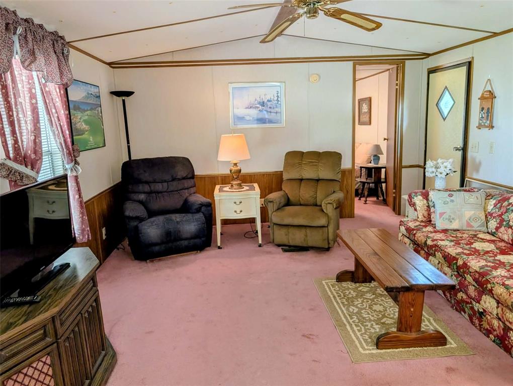 A living room features pink carpeting, a floral sofa, two recliners, and a wooden coffee table — 14181 SE 90TH TERRACE, SUMMERFIELD, FL