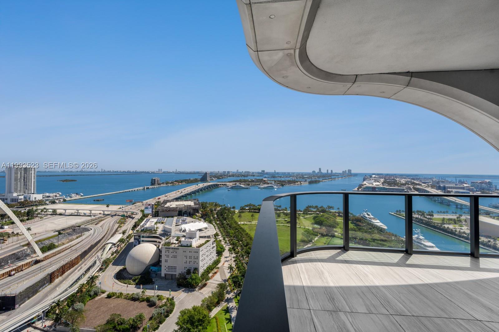 A high-rise balcony overlooks a bay, a bridge, and a city skyline — 1000 Biscayne Blvd # 2702, Miami FL 33132, MIAMI, FL