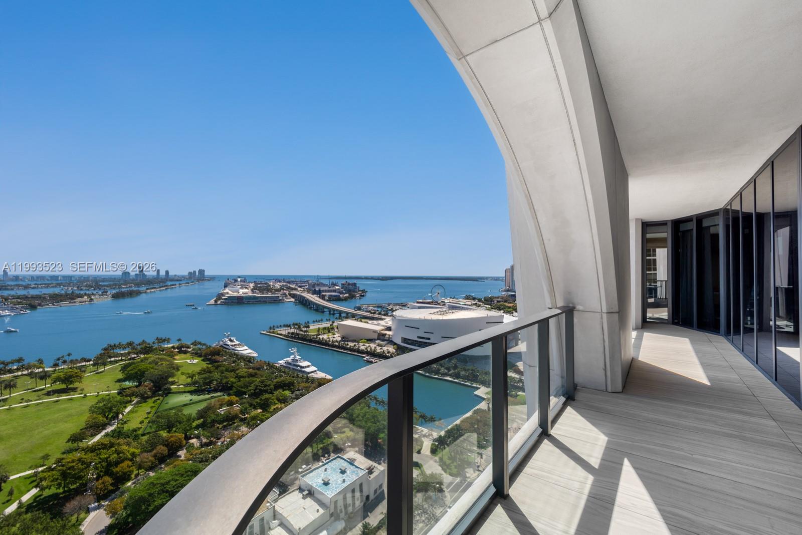 A high-rise balcony overlooks a bay, a park, and a city skyline — 1000 Biscayne Blvd # 2702, Miami FL 33132, MIAMI, FL
