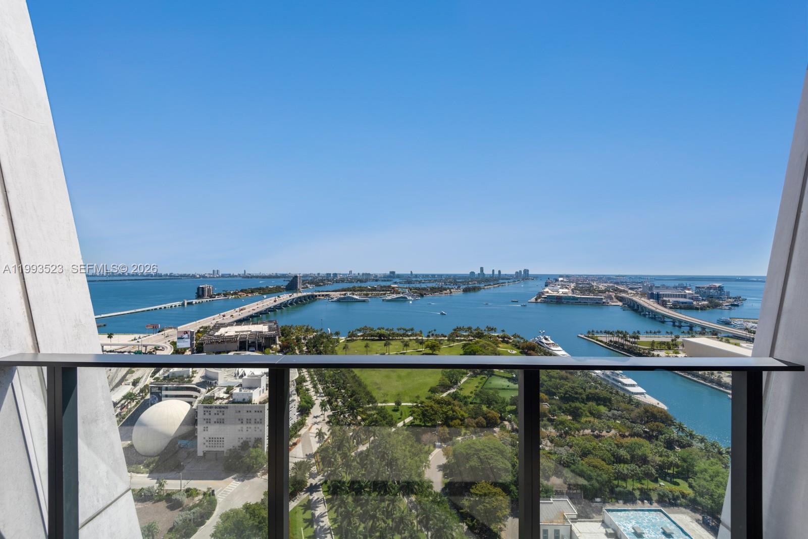A high-angle view from a balcony overlooks a park, a bay, and city bridges — 1000 Biscayne Blvd # 2702, Miami FL 33132, MIAMI, FL