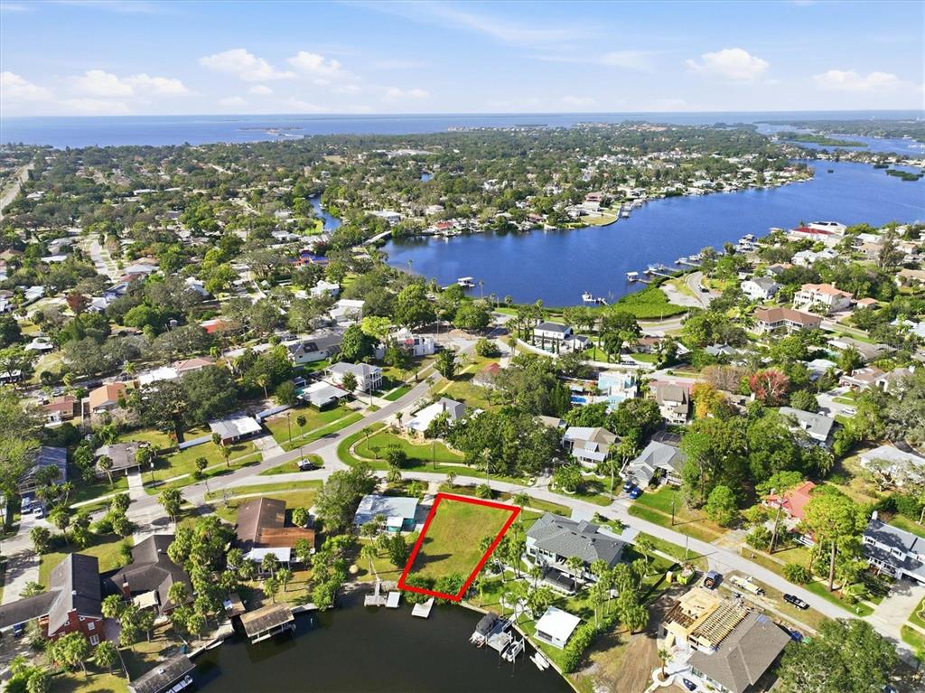 An aerial view shows a vacant waterfront lot outlined in red in a residential neighborhood — 56 INNESS DRIVE, TARPON SPRINGS, FL