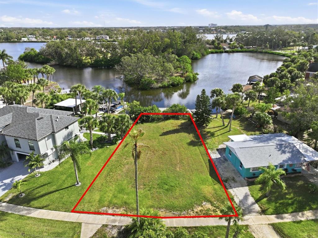 An aerial view shows a vacant, rectangular waterfront lot outlined in red between two houses — 56 INNESS DRIVE, TARPON SPRINGS, FL