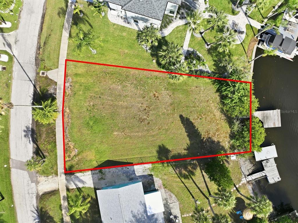 An aerial view shows a vacant, rectangular waterfront lot outlined in red — 56 INNESS DRIVE, TARPON SPRINGS, FL