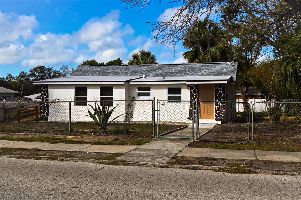 A single-story house with a white exterior, stone accents, and a chain-link fence — 426 S DISSTON AVENUE, TARPON SPRINGS, FL