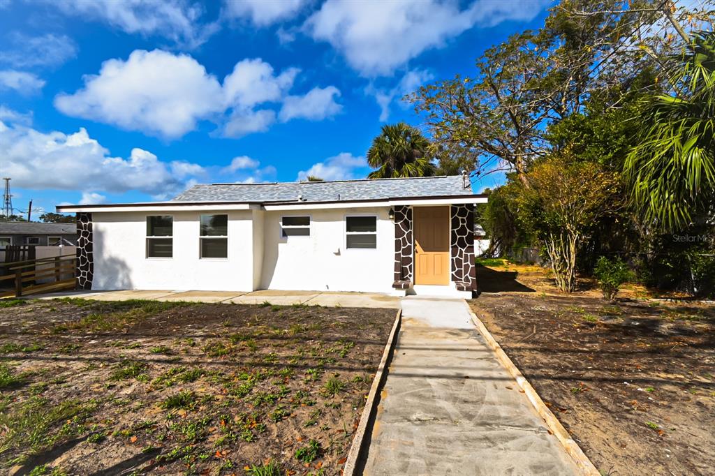 A single-story house with white stucco walls, stone accents, and a concrete walkway — 426 S DISSTON AVENUE, TARPON SPRINGS, FL
