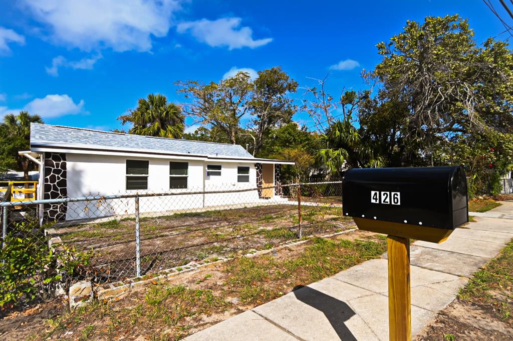 A single-story white house with a chain-link fence and a black mailbox in the foreground — 426 S DISSTON AVENUE, TARPON SPRINGS, FL