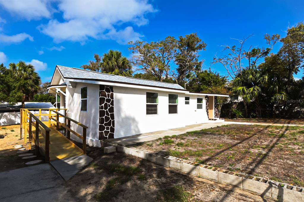 A white single-story house features a wooden wheelchair ramp and decorative stone corner accents — 426 S DISSTON AVENUE, TARPON SPRINGS, FL