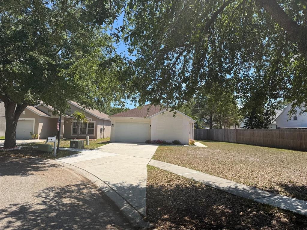 A single-story house with a white garage and a large front yard under trees — 11106 HAVASU COURT, RIVERVIEW, FL