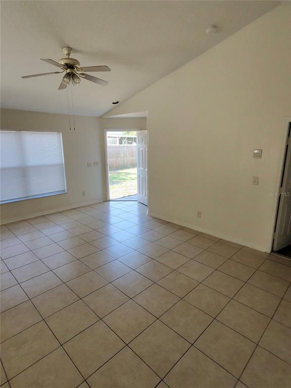 An interior view of a room with tiled floors, a ceiling fan, and a door — 11106 HAVASU COURT, RIVERVIEW, FL