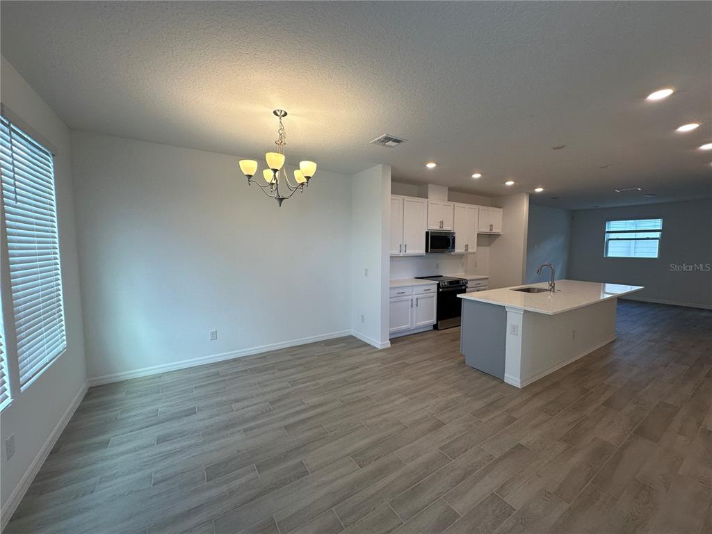 An open-concept kitchen and dining area features white cabinetry, a central island, and wood-look flooring — 6541 CYRILS DRIVE, ST CLOUD, FL
