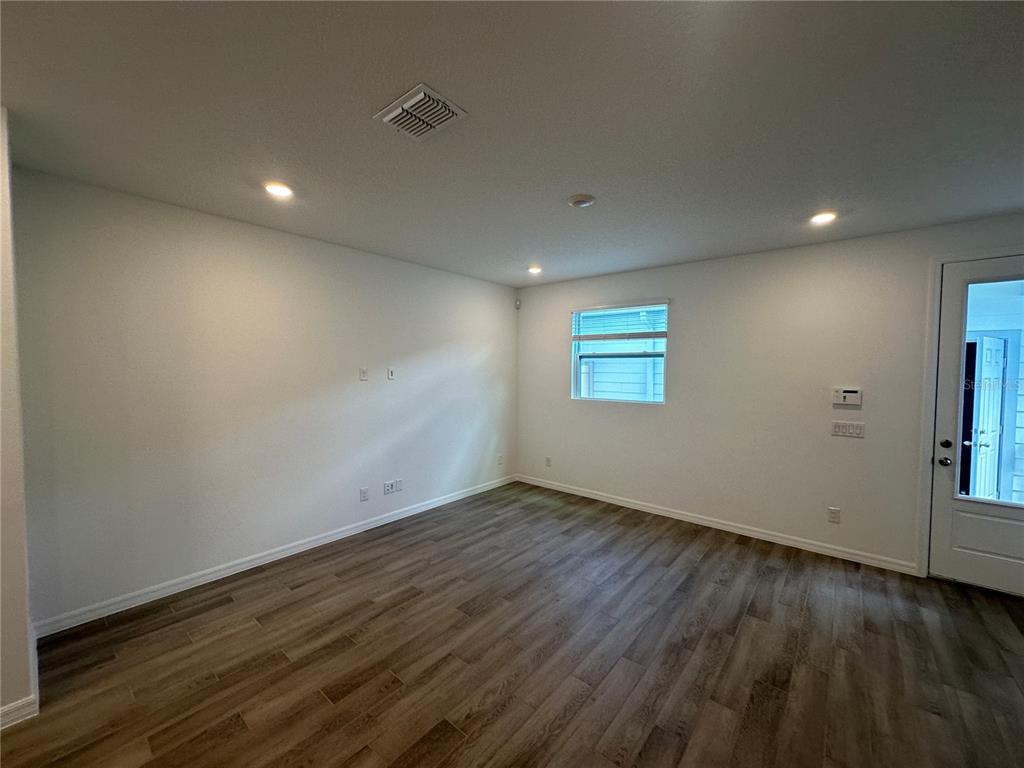 An empty room with white walls, recessed lighting, and wood-look flooring features a single window — 6541 CYRILS DRIVE, ST CLOUD, FL