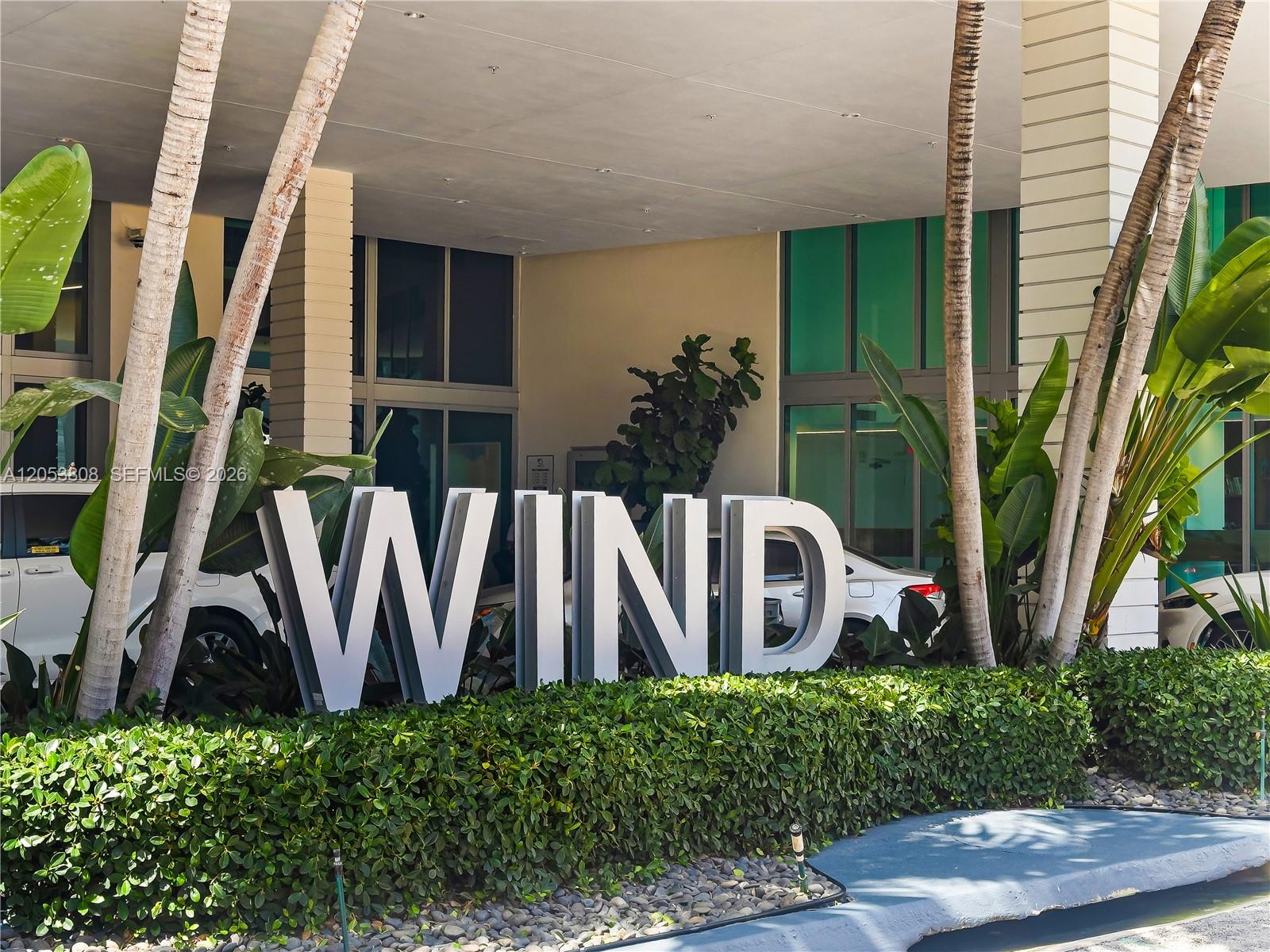 A large white sign spelling WIND stands in front of a modern building entrance — 350 S Miami Ave # 2102, Miami FL 33130, MIAMI, FL