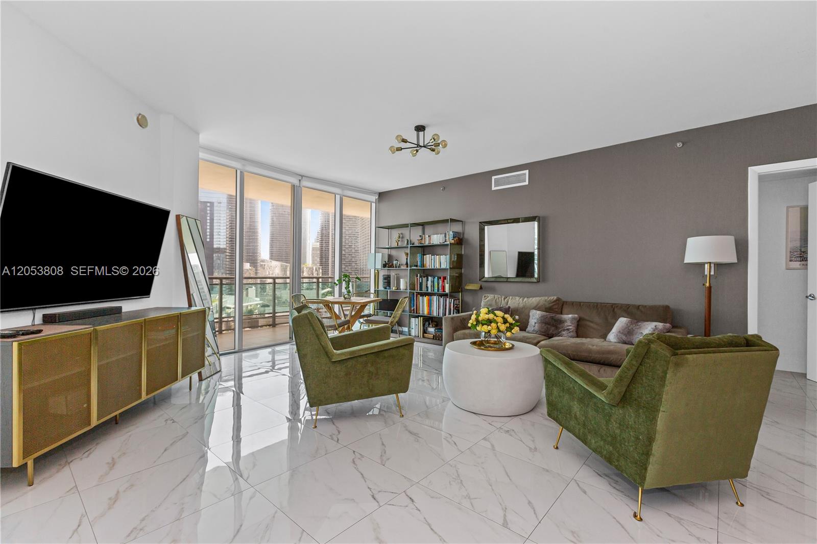 A modern living room features marble floors, green velvet armchairs, and a view of skyscrapers — 350 S Miami Ave # 2102, Miami FL 33130, MIAMI, FL