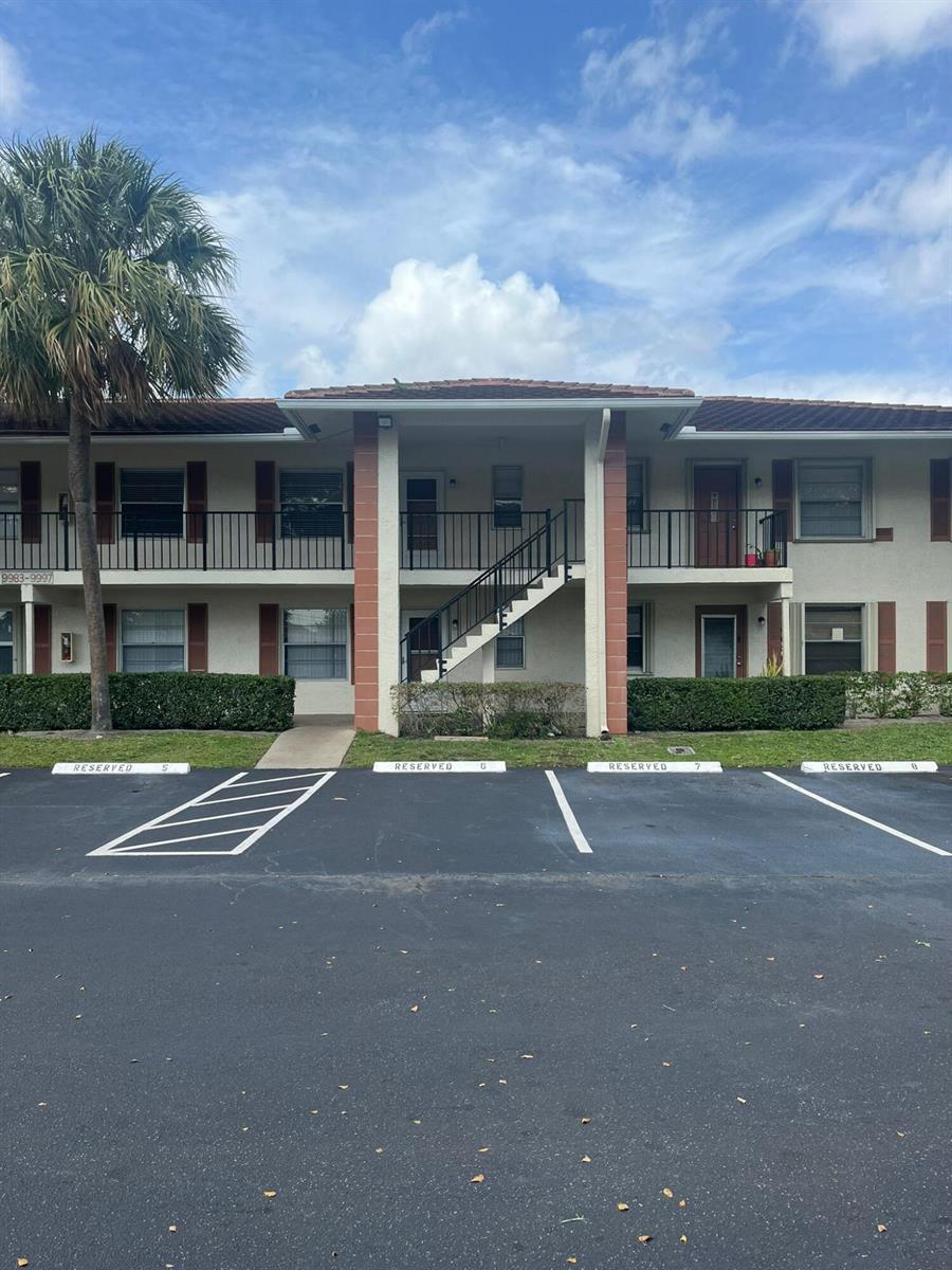 A two-story apartment building features a central staircase and reserved parking spaces in front — 9993 Three Lakes Circle, Boca Raton FL 33428, BOCA RATON, FL