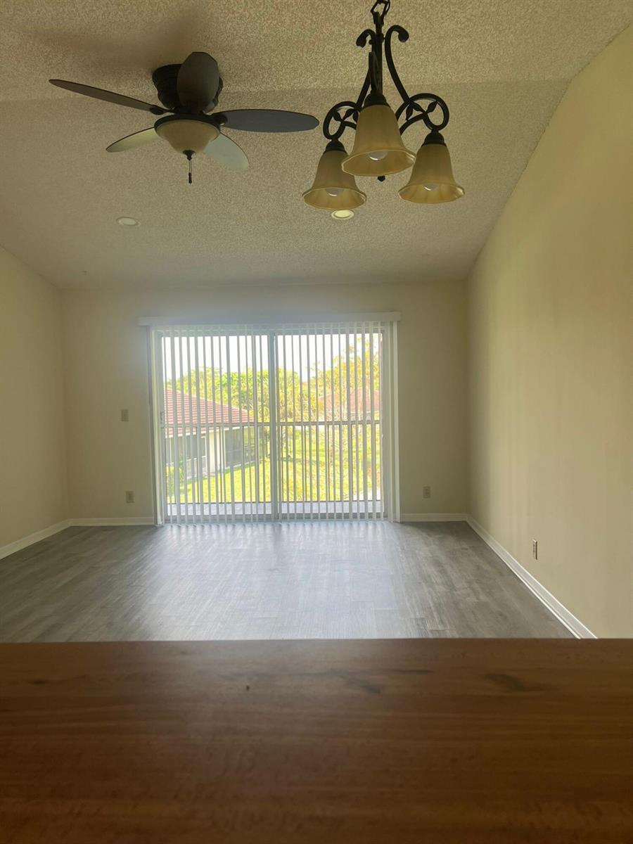 A dining area with wood-look flooring, a ceiling fan, a chandelier, and sliding glass doors — 9993 Three Lakes Circle, Boca Raton FL 33428, BOCA RATON, FL