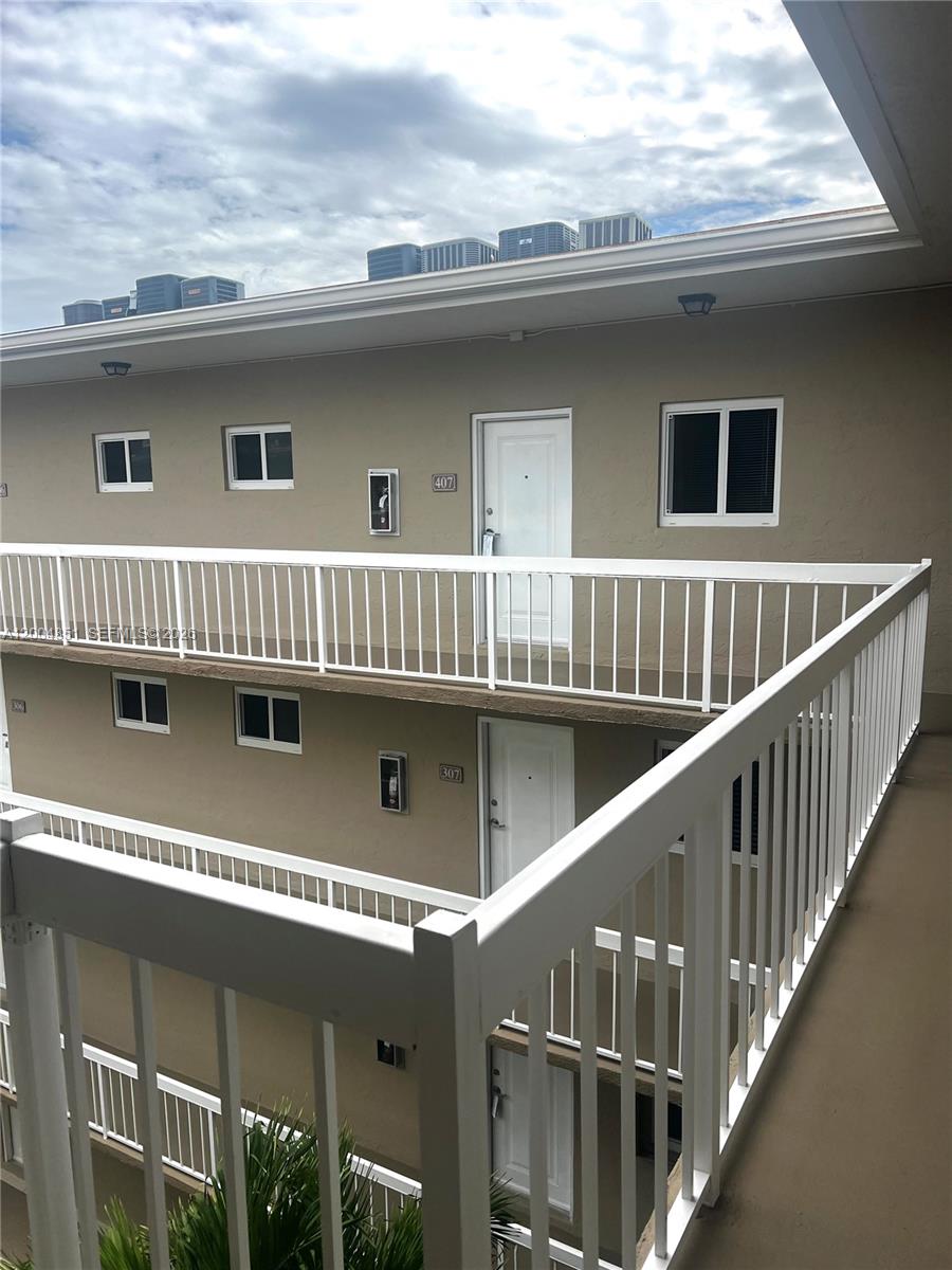 An exterior view of a multi-story apartment building with white railings and tan walls — 8103 Camino Real # 407, Miami FL 33143, MIAMI, FL