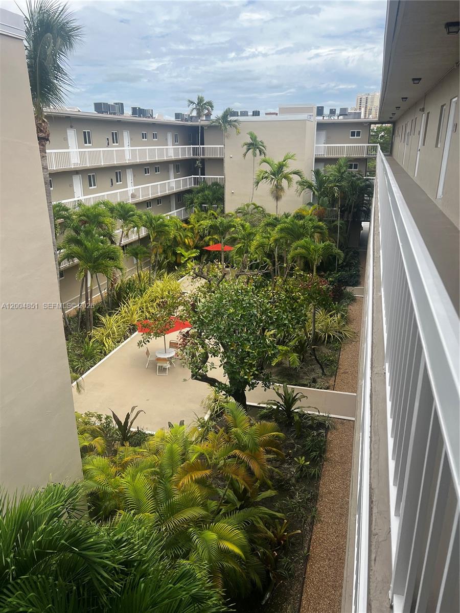 An elevated view of an apartment complex courtyard featuring palm trees and patio furniture — 8103 Camino Real # 407, Miami FL 33143, MIAMI, FL