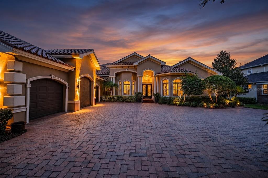 A single-story house with a paved driveway, garage, and arched windows at sunset — 1306 PLAYMOOR DRIVE, PALM HARBOR, FL