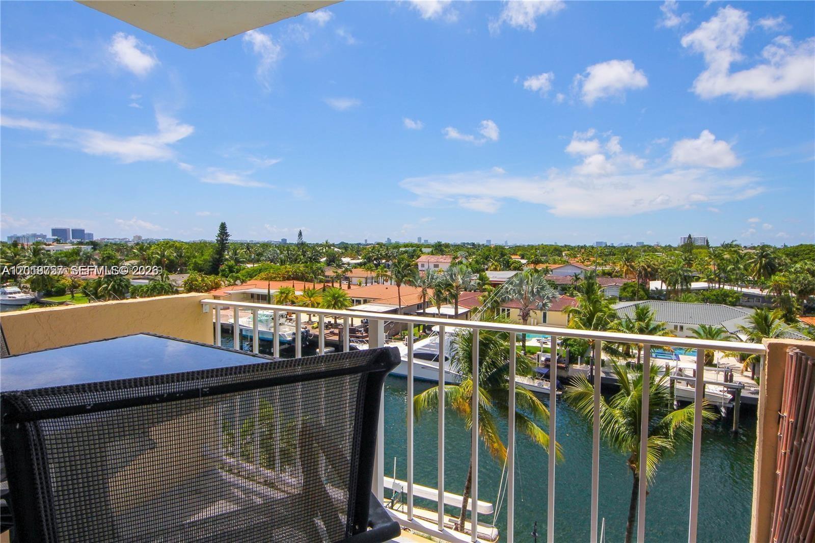 A balcony overlooks a canal with docked boats, palm trees, and residential houses — 2350 NE 135th St # 507, North Miami FL 33181, NORTH MIAMI, FL