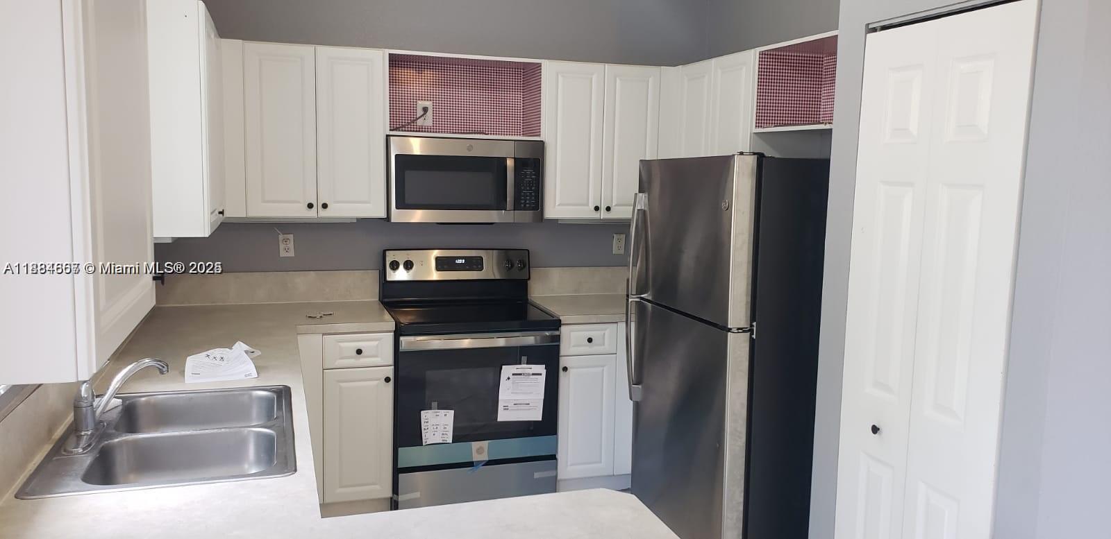 A kitchen features white cabinets, stainless steel appliances, and a double-basin sink — 60 SE 6th Rd, Homestead FL 33030, HOMESTEAD, FL